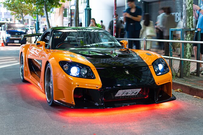 Orange and black Veilside RX-7 like Han's Tokyo Drift car parked on a Tokyo street at night